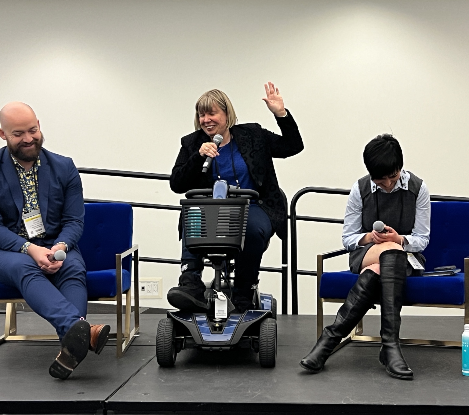 Darby laughing and raising a hand while speaking on a panel